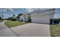 Charming house showing the manicured lawn, lush shrubbery, and a two-car garage at 408 Bloomingdale Dr, Davenport, FL 33897