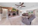 Spacious living room with a brick fireplace, ceiling fan, large windows, and tile flooring at 6441 Nightwind Cir, Orlando, FL 32818