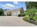 Side view of the garage featuring a brick-paved driveway and lush green landscaping with a palm tree and shrubbery at 8214 Lake Serene Dr, Orlando, FL 32836
