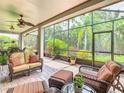 Relaxing screened-in porch with comfortable seating, ceiling fans, and views of the lush backyard at 125 Prima Dr, Poinciana, FL 34759