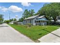 Gray home featuring a fenced yard, blue porch roof, and lush landscaping at 1322 New York Ave, St Cloud, FL 34769