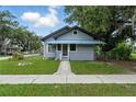 A gray, fenced home with a blue metal porch roof and walkway at 1322 New York Ave, St Cloud, FL 34769