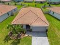 Aerial shot of home featuring tile roof, two car garage and green lawn, surrounded by neighboring houses at 1416 Oak Marsh St, Davenport, FL 33837