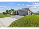 Single-story home with green lawn, paver driveway, two-car garage, and tropical palm tree landscaping at 1416 Oak Marsh St, Davenport, FL 33837