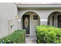 Charming home entry with an arched doorway, decorative glass door, and neatly trimmed green hedges at 196 Canterbury Bell Dr, Oviedo, FL 32765