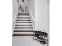 Well-lit staircase with wooden steps and white railings; shoe rack at 2525 Ridgeway Dr, Kissimmee, FL 34746