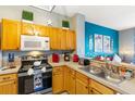 Efficient kitchen with oak cabinets, modern appliances, and a breakfast bar overlooking the living room at 2585 Maneshaw Ln, Kissimmee, FL 34747