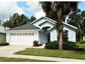 Attractive home showcasing a lovely manicured front lawn, complemented by mature trees and a 2-car garage at 2591 Oneida Loop, Kissimmee, FL 34747