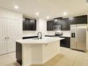 Modern kitchen with stainless steel appliances, a large island, and dark cabinetry at 2833 Noble Crow Dr, Kissimmee, FL 34744