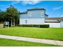 Two-story home has a grassy backyard with green bushes, blue accents, and a 'For Sale' sign at 2862 Grasmere View Pkwy, Kissimmee, FL 34746