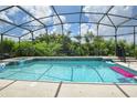 Screened-in pool with clear blue water, surrounded by lush greenery and blue sky with clouds at 344 Cherokee Ave, Haines City, FL 33844