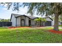 Well-maintained single-story home with grey walls, black trim, mature landscaping, and two-car garage at 6528 Shepherd Oaks Pass, Lakeland, FL 33811
