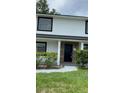 Charming home exterior featuring a black front door with wood-look siding and manicured bushes in front at 124 Cinnamon Dr, Orlando, FL 32825