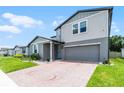 Charming two-story home with light-blue shutters, attached garage, and brick paver driveway at 1538 Mermaid Way, Haines City, FL 33844