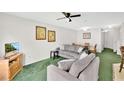 Cozy living room with comfortable seating, green carpet, and ample light at 2855 Club Cortile Cir, Kissimmee, FL 34746