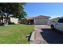 Charming single-story home featuring a red tile roof, brick driveway, and well-maintained landscaping at 455 Cinnamon Dr, Kissimmee, FL 34759