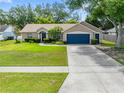 Inviting single-story home featuring a well-kept lawn, mature trees, and a blue two-car garage door at 4828 Jeanette Ct, St Cloud, FL 34771