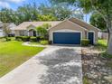 Attractive single-story home with a well-manicured lawn, mature trees, and a blue two-car garage door at 4828 Jeanette Ct, St Cloud, FL 34771