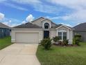 Charming single-story home with a well-manicured lawn, inviting entrance, and two-car garage at 973 Corvina Dr, Davenport, FL 33897