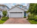 A two-story home with a brick driveway, blue front door, and a two-car garage at 2740 Picasso Ct, Kissimmee, FL 34743