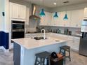 Modern kitchen featuring white cabinets, stainless steel appliances, a kitchen island, and stylish pendant lighting at 3184 Songbird Cir, Harmony, FL 34773