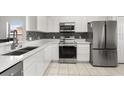 The kitchen features stainless steel appliances, white cabinetry, and a decorative backsplash at 3217 Whooping Crane Run, Kissimmee, FL 34741