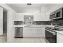 Modern kitchen featuring stainless steel appliances, white cabinetry, and decorative backsplash at 3217 Whooping Crane Run, Kissimmee, FL 34741