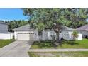 Inviting one-story home with lush front lawn and an attached two-car garage, shaded by a mature tree at 478 Acacia Tree Way, Kissimmee, FL 34758