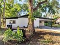Charming home with a white exterior, black roof, and a covered carport at 7043 Carlene Dr, Orlando, FL 32835