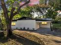 Charming home with a white exterior, black roof, and a covered carport at sunset at 7043 Carlene Dr, Orlando, FL 32835