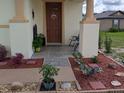 Inviting front porch with a decorative door and a well-maintained, beautifully landscaped garden at 1405 Hillsborough Way, Kissimmee, FL 34759