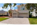 View of the attached two-car garage and brick driveway showcasing the home's exterior and landscaping at 1950 Windward Oaks Ct, Kissimmee, FL 34746