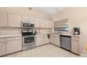 Bright kitchen featuring stainless steel appliances, light wood cabinets, and tiled flooring at 2569 Tandori Cir, Orlando, FL 32837