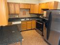 Functional kitchen with stainless steel appliances, wood cabinets, and dark countertops at 2619 Milton Ave, Kissimmee, FL 34741