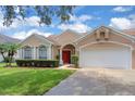 Inviting home with a red front door, lush landscaping, and a well-maintained lawn at 651 Regina Cir, Oakland, FL 34787