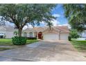 Charming single-story home featuring a well-manicured lawn, arched windows, and a three-car garage at 651 Regina Cir, Oakland, FL 34787