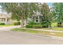 Gray two-story home featuring manicured landscaping with flowering bushes and green lawn at 6808 Goldflower Ave, Harmony, FL 34773