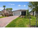 Inviting single-story home featuring lush landscaping, a paver driveway, and a screened porch at 1309 Lombardi Ct, Kissimmee, FL 34759