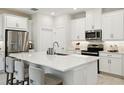 Bright kitchen featuring white cabinets, stainless steel appliances, and a spacious island with seating at 1309 Lombardi Ct, Kissimmee, FL 34759
