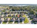 Neighborhood aerial view showcases the home, white fencing, sidewalks, and a large lake in the distance at 1383 Buckeye Trace Blvd, Winter Haven, FL 33881