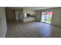 Open-concept living room with tile flooring, sliding glass doors and an adjacent kitchen area at 15 Clear Way, Ocala, FL 34472
