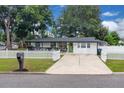 Landscaped front yard featuring green lawn, driveway, and white picket fence enhancing curb appeal at 1710 Thor Ave, Apopka, FL 32703