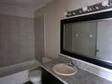Tiled bathroom featuring a vanity with a large framed mirror and a shower-tub combo at 2030 Cascades Blvd # 204, Kissimmee, FL 34741