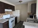 Classic kitchen with modern countertops, dark wood cabinets, and white appliances at 2030 Cascades Blvd # 204, Kissimmee, FL 34741