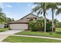 Inviting home showcasing a well-maintained lawn, mature palms, and an attached two-car garage at 2612 Keswick Ct, Kissimmee, FL 34744