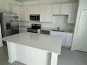Bright modern kitchen featuring stainless steel appliances, a center island, and white cabinets at 2626 Skyline Loop, Kissimmee, FL 34758
