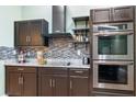 Contemporary kitchen features sleek dark cabinetry, stainless steel appliances, tile backsplash and granite countertops at 2695 Hilliard Ct, Kissimmee, FL 34744