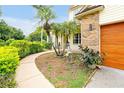 Charming front yard featuring a curved walkway, landscaped garden beds, and a modern wood-tone garage door at 3109 Harvest Ln, Kissimmee, FL 34744