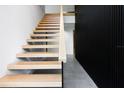 Modern staircase featuring light wood treads, sleek railing, and distinctive black accent wall at 3807 S Semoran Blvd, Orlando, FL 32822