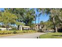 Community entrance sign amidst lush landscaping and mature trees. Includes gated entry and signage at 5287 Images Cir # 303, Kissimmee, FL 34746